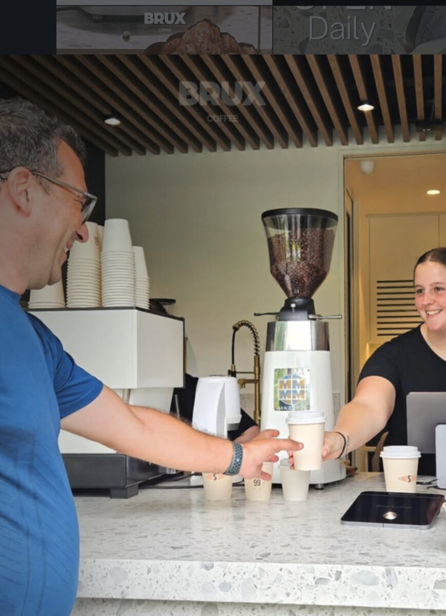 Friendly barista serving coffee at Brux Coffee