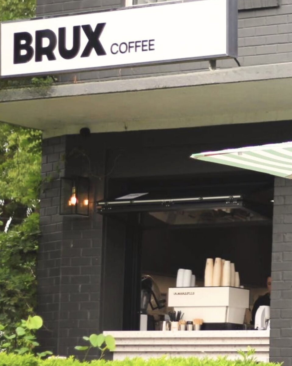 Brux Coffee storefront with signage and greenery